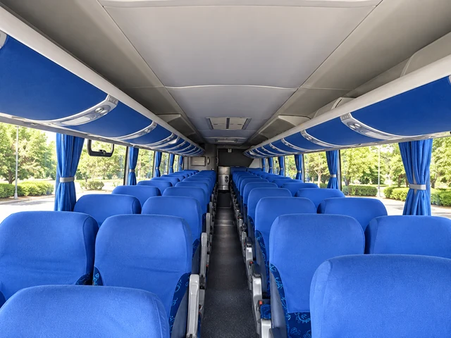 Interior de um dos ônibus da AWM, com poltronas azuis e bagageiros superiores